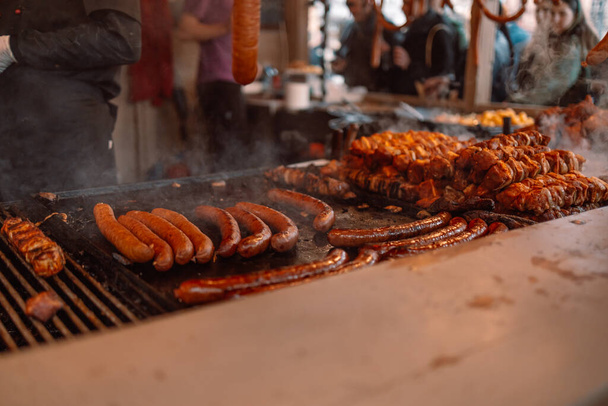 Blurry background of bbq street food for sale. Fried baked sausages, hot dog on street food outdoor market stall in Krakow Poland  - Photo, Image