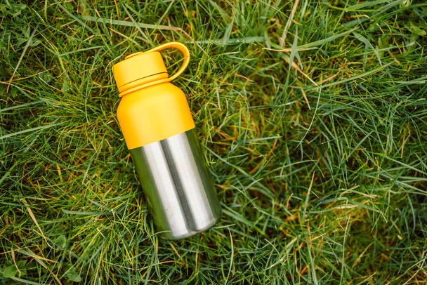 Water bottle. Reusable steel thermo water bottle on green grass. Steel thermo water bottle  - Фото, зображення