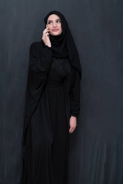 Young modern Muslim businesswomen using smartphones wearing hijab clothes in front of a black chalkboard. - 写真・画像
