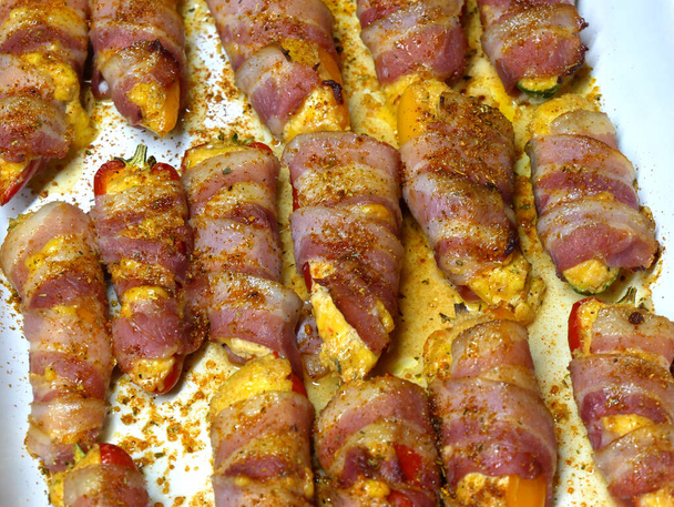 Preparation of a dish called Jalapeno poppers, composed of jalapeno peppers stuffed with cheese, sopasco and rolled with a slice of smoked bacon. - Photo, Image
