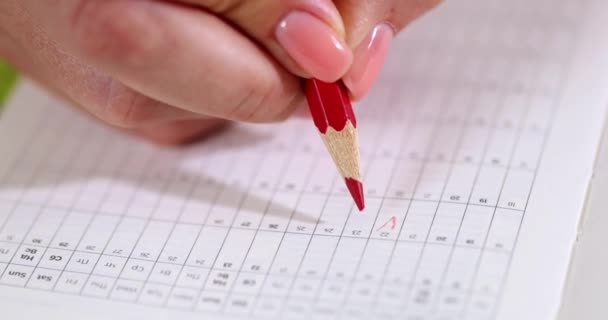 Femme marque les jours du cycle menstruel dans le calendrier avec crayon rouge gros plan film 4k au ralenti. Planification de la grossesse concept de suivi de l'ovulation - Séquence, vidéo