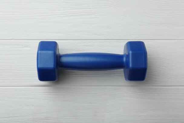 One blue dumbbell on white wooden table, top view - Фото, изображение