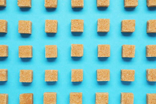 Brown sugar cubes on turquoise background, flat lay - Foto, Bild