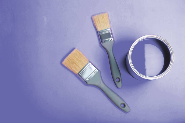Tin can with paint and brushes on violet background, flat lay. Space for text - Photo, Image