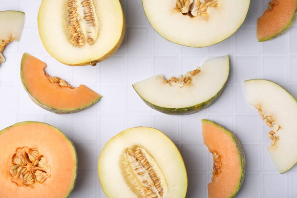 Tasty colorful ripe melons on white checkered table, flat lay - Foto, Bild