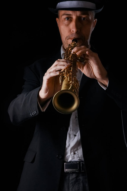 soprano saxophone in the hands of a guy on a black background - Photo, Image