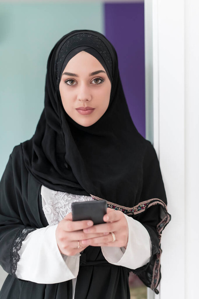 young modern Muslim businesswomen using smartphones to wear traditional hijab clothes at home. High quality photo - Foto, afbeelding