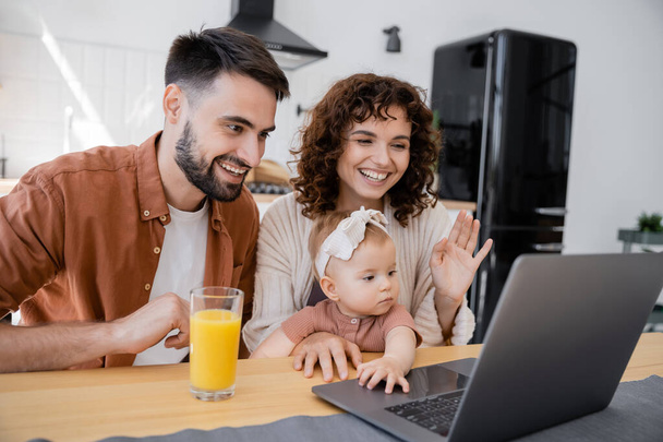 cheerful family with infant child having video call on laptop at home - Foto, immagini
