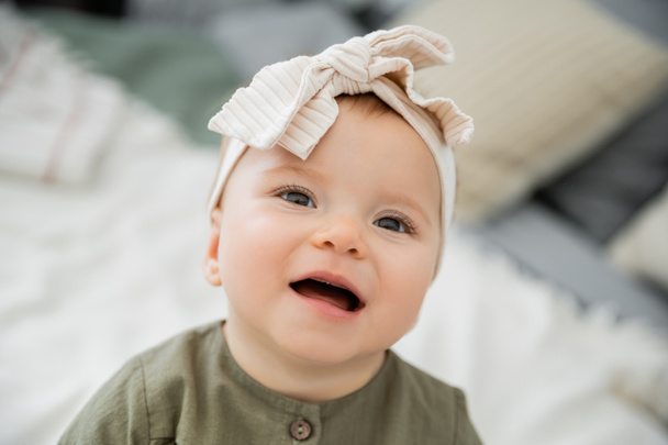 portrait of happy baby girl in pastel pink headband with bow  - 写真・画像