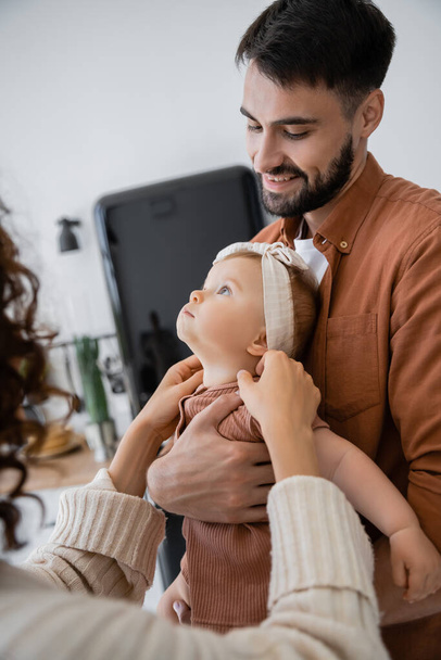 happy bearded father holding in arms baby daughter near wife at home - Φωτογραφία, εικόνα