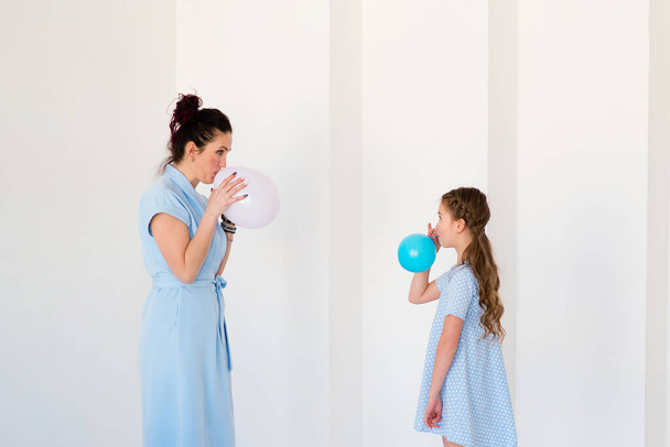 Mom and daughter have fun in the room. Inflate balloons. - Photo, image