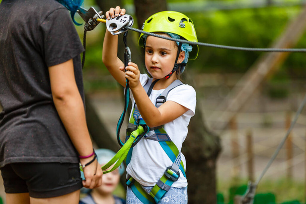 Happy school girl enjoying activity in a climbing adventure park on a summer day - Foto, immagini