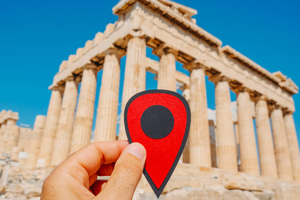 Yunanistan 'ın başkenti Atina' da bulunan ünlü Parthenon 'un kalıntılarını gösteren kırmızı bir işaret taşıyan bir adamın eli. - Fotoğraf, Görsel