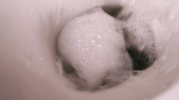 Toilette in ceramica durante un rossore, primo piano dall'alto. Pulizia del bagno con schiuma. WC di casa con un blocco odore rosa. - Filmati, video
