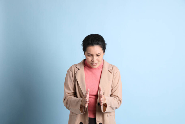 Starší asijské žena s růžovou košili hnědé sako na modrém pozadí. - Fotografie, Obrázek