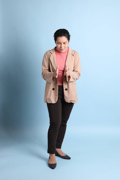 The senior Asian woman with pink shirt brown blazer on the blue background. - Fotó, kép