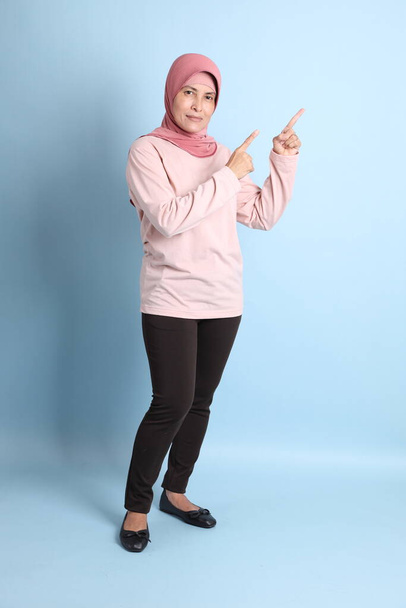 The senior southeast Asian woman with hijab standing on the blue background - Foto, Imagem