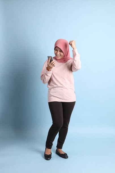 The senior southeast Asian woman with hijab standing on the blue background - Zdjęcie, obraz