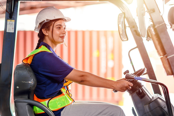 female forklift operator working in a warehouse. Portrait of young Indian woman driver sitting in forklift and smiling working in large warehouse - Foto, Bild