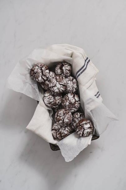 Chocolate Crinkle iced biscuits arranged on a white marble kitchen work surface with copy space available. Home baking concept image. - Photo, Image