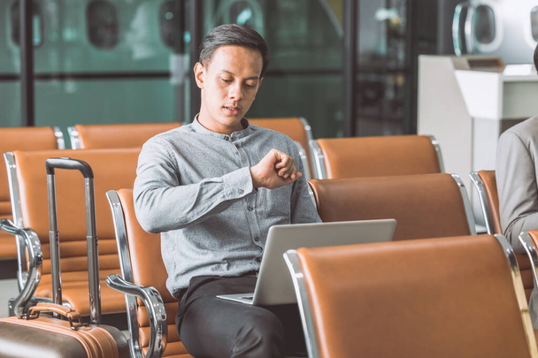 uomo d'affari noioso in aeroporto in attesa dal ritardo del volo ore tardi guardando orologio da polso e preoccupato - Foto, immagini