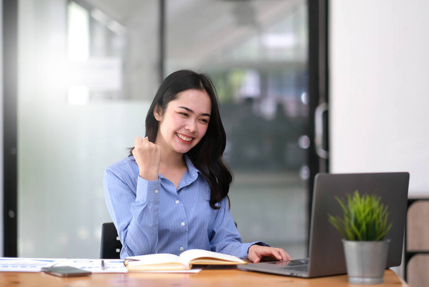 Pretty Asian businesswoman sitting on a laptop And the work came out successfully and the goal was achieved, happy and satisfied with her - Photo, image