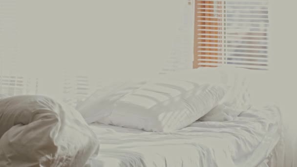 Weißes Bett in der Nähe des Jalousie-Fensters mit weißen beweglichen Vorhängen am Zugluft.Schiebebewegung - Filmmaterial, Video