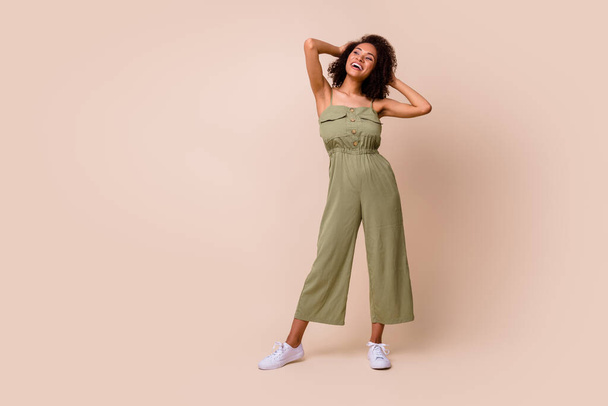 Full body photo of cute young woman wavy hair enjoy new hairdo look empty space wear trendy khaki look isolated on beige color background. - Foto, afbeelding