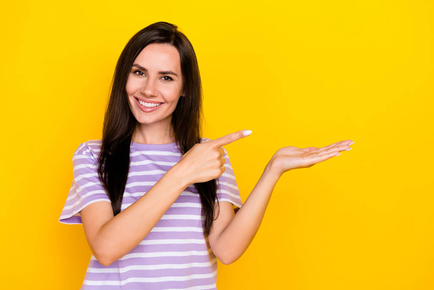 Photo of young attractive gorgeous nice woman hold hand finger pointing new product recommend isolated on yellow color background. - Valokuva, kuva