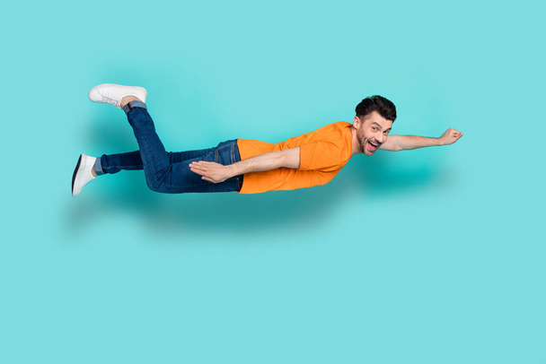 Profile side full body photo of excited crazy guy flying fast ahead isolated on cyan color background. - Foto, afbeelding