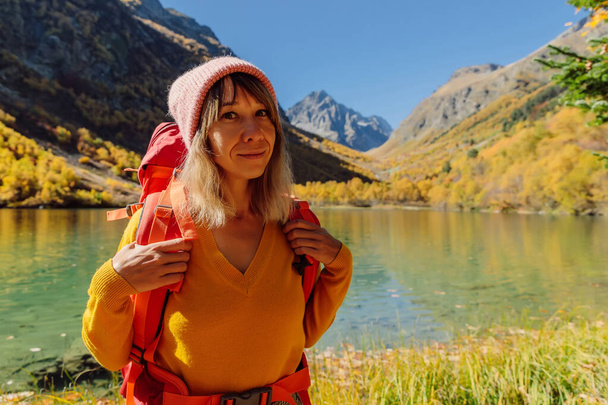 Traveller woman at lake in the autumnal mountains. Mountain lake and hiker tourist - Fotografie, Obrázek