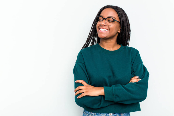 Νεαρή Αφροαμερικανή γυναίκα απομονωμένη σε λευκό φόντο χαμογελώντας με σταυρωμένα τα χέρια. - Φωτογραφία, εικόνα