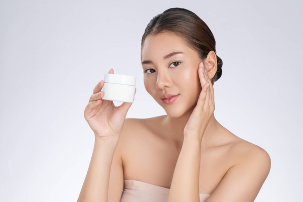Gorgeous woman smiling holding mockup product for advertising text place, light grey background. Concept of healthcare for skin, beauty care product for advertising. - 写真・画像