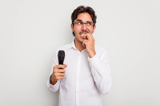 jovem cantor hispânico homem isolado no fundo branco mordendo unhas, nervoso e muito ansioso. - Foto, Imagem