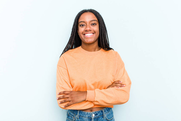 Young African American woman with braids hair isolated on blue background who feels confident, crossing arms with determination. - Foto, afbeelding