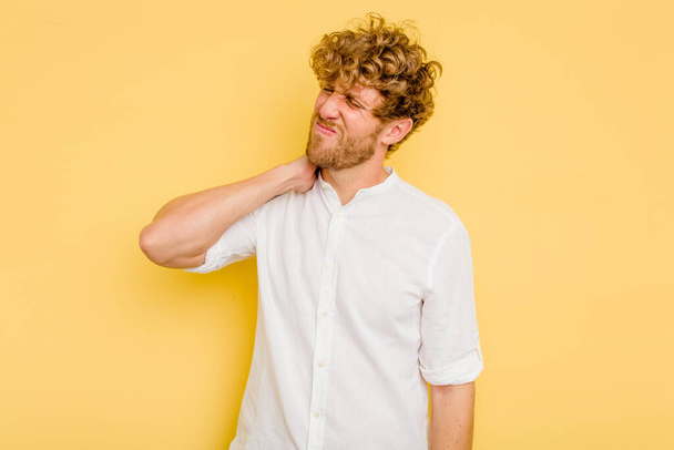 Young caucasian man isolated on yellow background having a neck pain due to stress, massaging and touching it with hand. - Foto, Bild