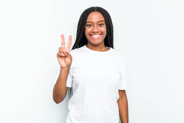jonge afrikaanse amerikaanse vrouw geïsoleerd op witte achtergrond tonen overwinning teken en brede glimlach. - Foto, afbeelding
