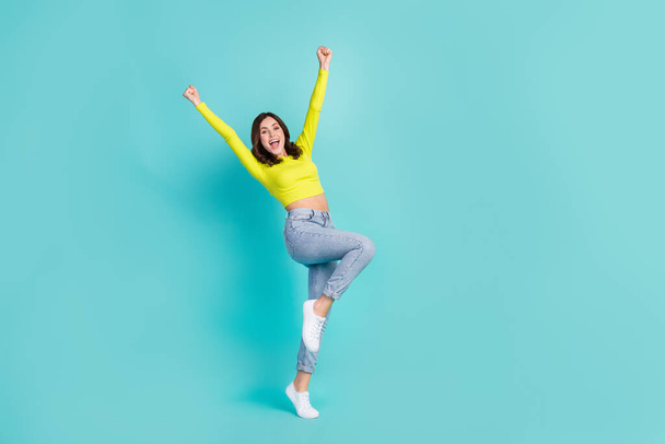 Full size photo of young attractive sporty slender woman wear casual clothes fists up hooray weekend isolated on cyan color background. - Foto, immagini