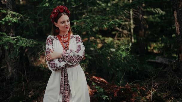 Pretty woman in traditional ukrainian necklace, dress on green nature backdrop. Lady in national costume - vyshyvanka in Carpathian mountans. High quality  - Φωτογραφία, εικόνα