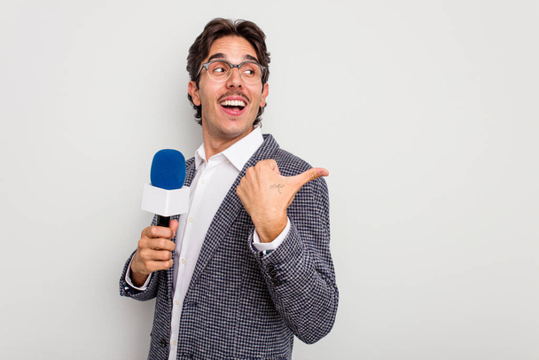 Junger hispanischer Fernsehmoderator isoliert auf weißem Hintergrund, Daumenfinger weg, lachend und unbeschwert. - Foto, Bild