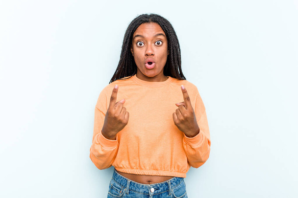 Jonge Afro-Amerikaanse vrouw met vlechten haar geïsoleerd op blauwe achtergrond wijzen ondersteboven met geopende mond. - Foto, afbeelding