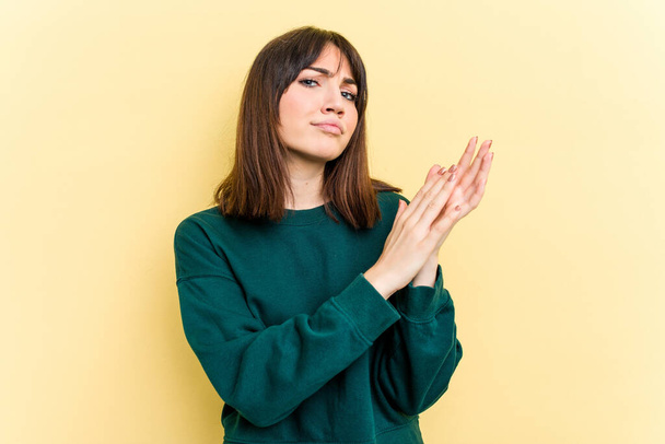 Young caucasian woman isolated on yellow background feeling energetic and comfortable, rubbing hands confident. - Фото, зображення