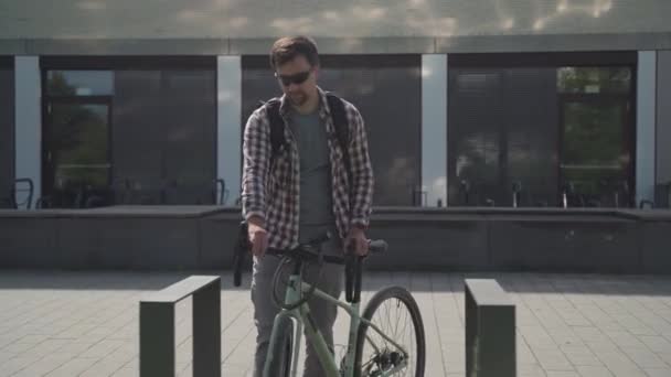 Bisikletçi Almanya 'da bisiklet parkına park eder ve bisikletini kilitler. Güvenlik ve ulaşım. Bisikleti park yerine kilitleyen adam. Bisiklet park alanındaki hırsızlık önleyici kilidi kapatmak için banliyö anahtarı kullan - Video, Çekim