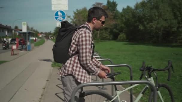 Ποδηλάτες πάρκα και κλειδώνει ποδήλατο σε δημόσιο χώρο στάθμευσης ποδηλάτων στη Γερμανία. Ασφάλεια και μεταφορά. Άντρας κλειδώνει ποδήλατο στο πάρκινγκ του δρόμου. Ο μεταφορέας χρησιμοποιεί το κλειδί για να κλείσει την αντικλεπτική κλειδαριά στο χώρο στάθμευσης ποδηλάτων - Πλάνα, βίντεο