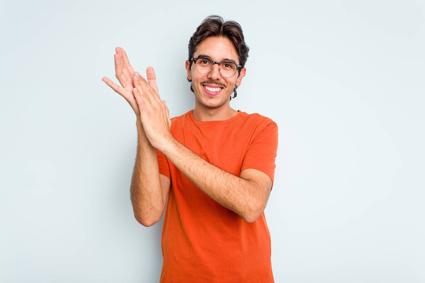 Young hispanic man isolated on blue background feeling energetic and comfortable, rubbing hands confident. - Zdjęcie, obraz