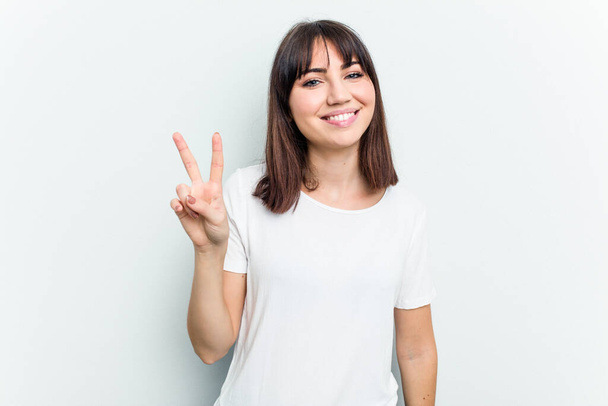 Young caucasian woman isolated on white background showing victory sign and smiling broadly. - Valokuva, kuva