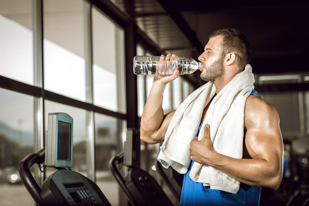 Young man drinking water in gym - Photo, image