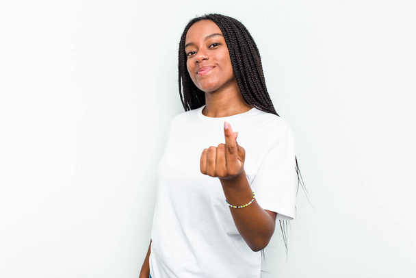 Young African American woman isolated on white background pointing with finger at you as if inviting come closer. - Фото, изображение