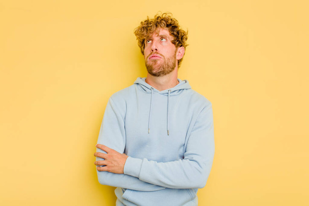 Young caucasian man isolated on yellow background tired of a repetitive task. - Photo, Image