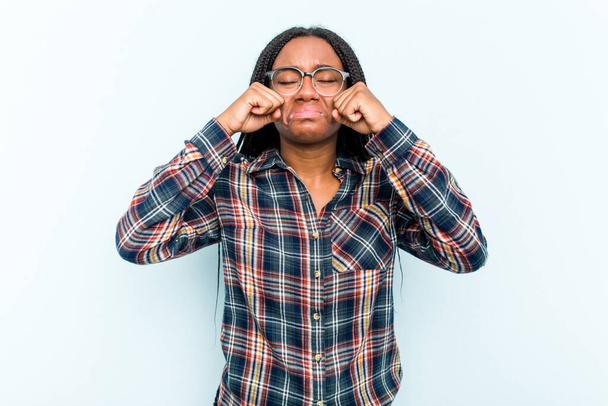 Mladá Afroameričanka s copánky vlasy izolované na modrém pozadí fňukání a pláč zoufale. - Fotografie, Obrázek